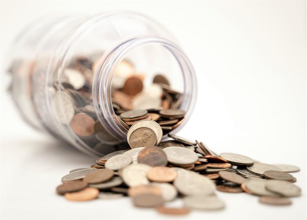 Glass jar spilling out copper coins, the featured image for misconceptions on home loan refinancing in Singapore