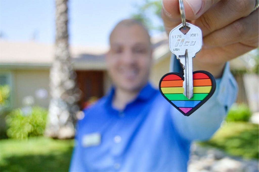 Man holding his house key with a rainbow heart token, happy that his family is protected under the Home Protection Scheme (HPS) in Singapore
