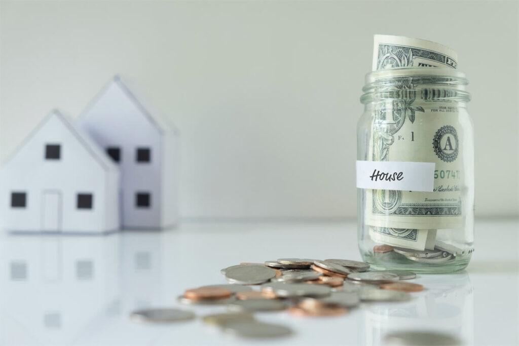 Image of a glass jar labelled ‘house’ with notes and coins to show the cost of HDB BTO homes in Singapore