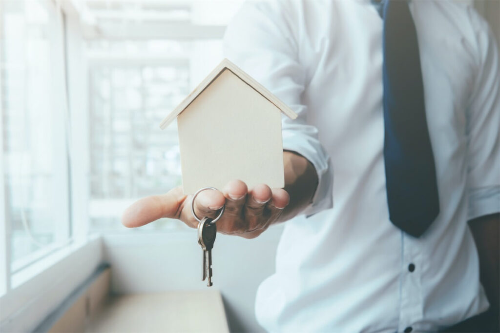 Man holding a miniature house and keys to show misconception that gifting of property in Singapore can result in lower property stamp duty