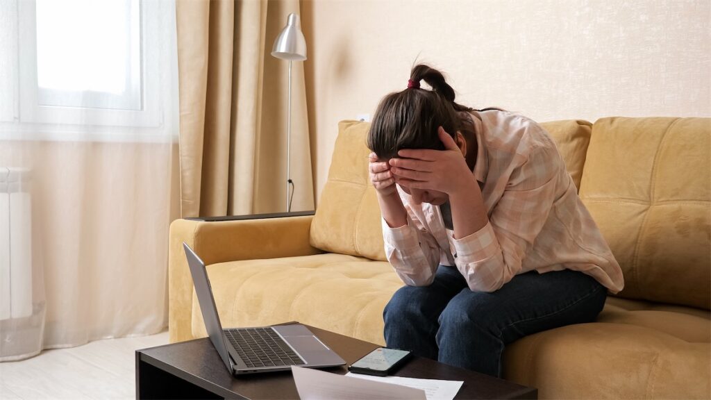 Woman burying her face in her hands, looking frustrated due to her bankruptcy history affecting her home loan in-principle approval