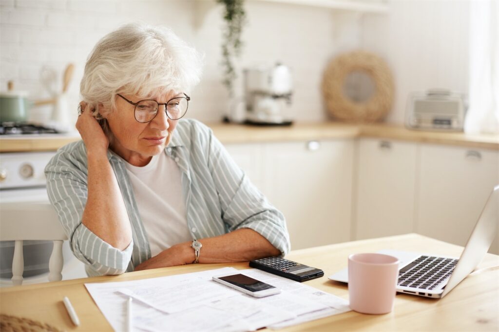 Elderly woman looking through her home loan in-principle approval application and considering the rejection due to her age