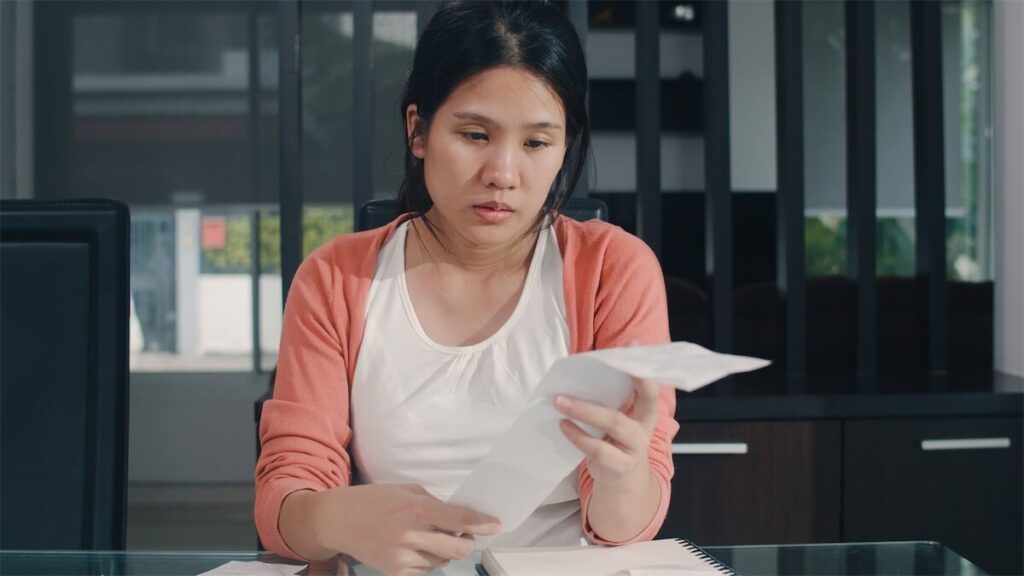  Image of a woman looking at bills in her home in Singapore