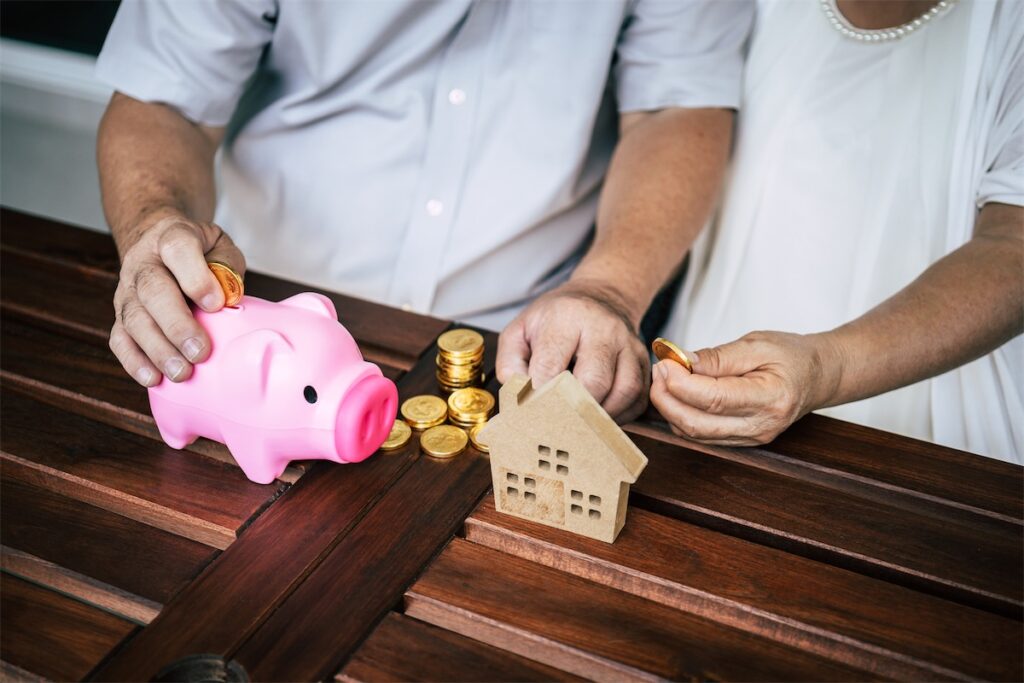 An elderly couple sitting by the bench and counting coins in their piggybank