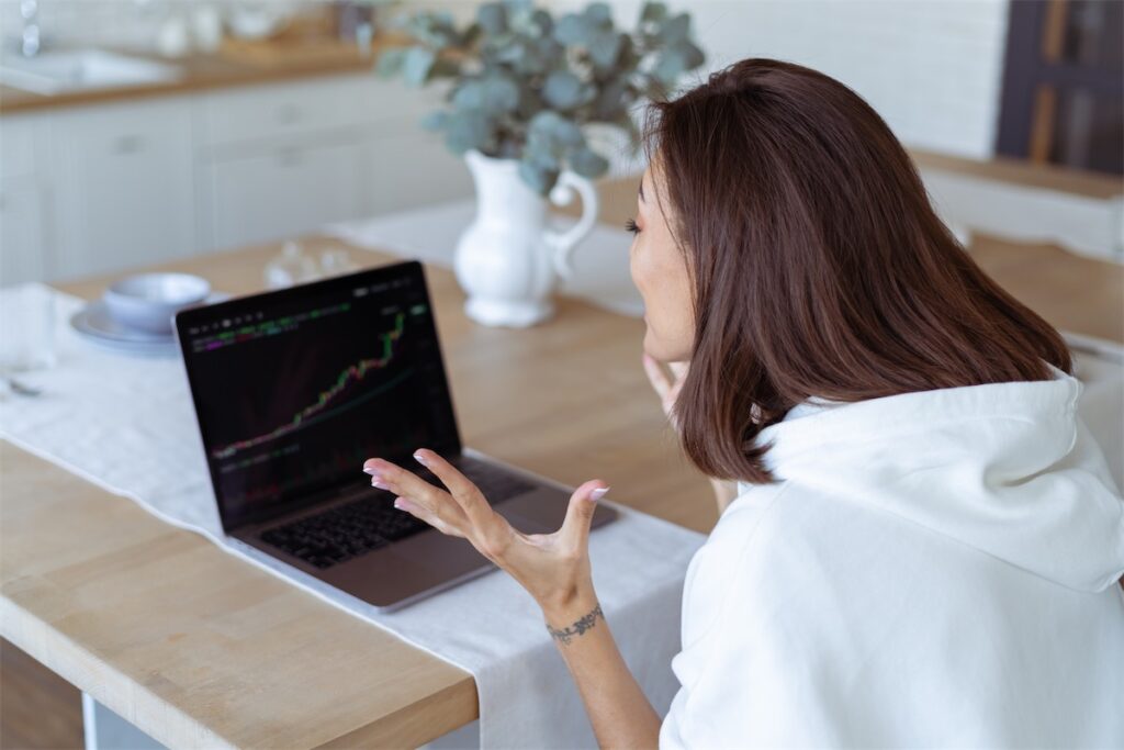 Young woman in her Singapore GCB home kitchen with a laptop showing a graph of growth on the screen 