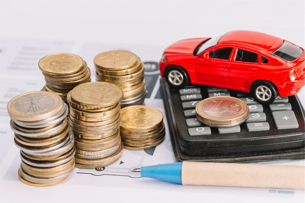  Image of stacks of coins, miniature car, calculator and pen to illustrate wealth tax in Singapore