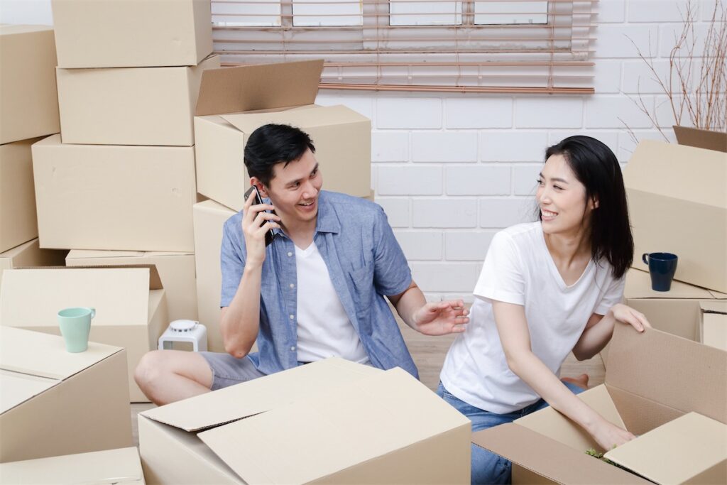 Image of a married couple moving into their first home in Singapore and on the phone with a home loan financing advisor to discuss the next step of their home loan journey.